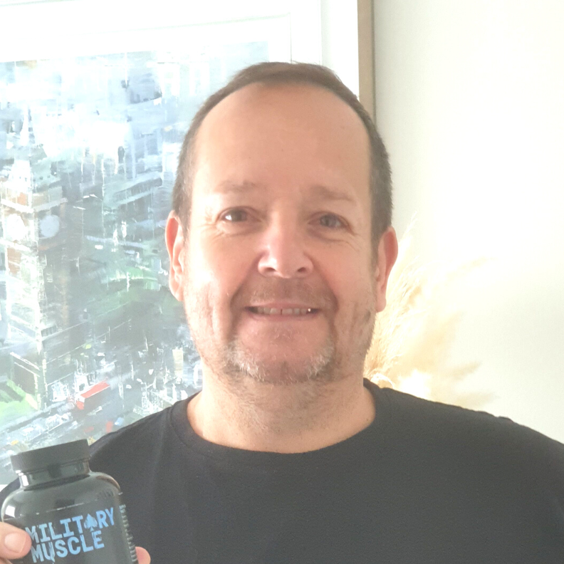 a man wearing a black tee shirt holding a package of military muscle 