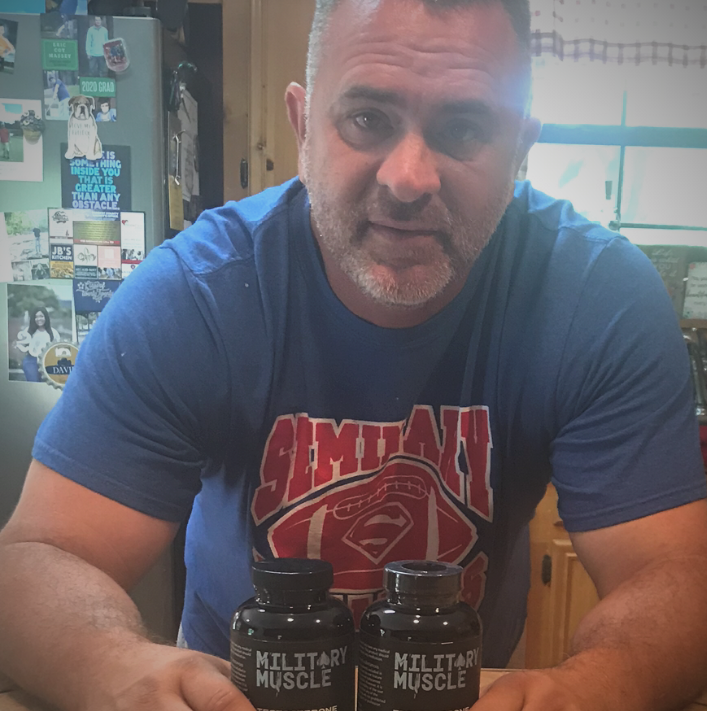 a man in a kitchen setting holding a package of military muscle 